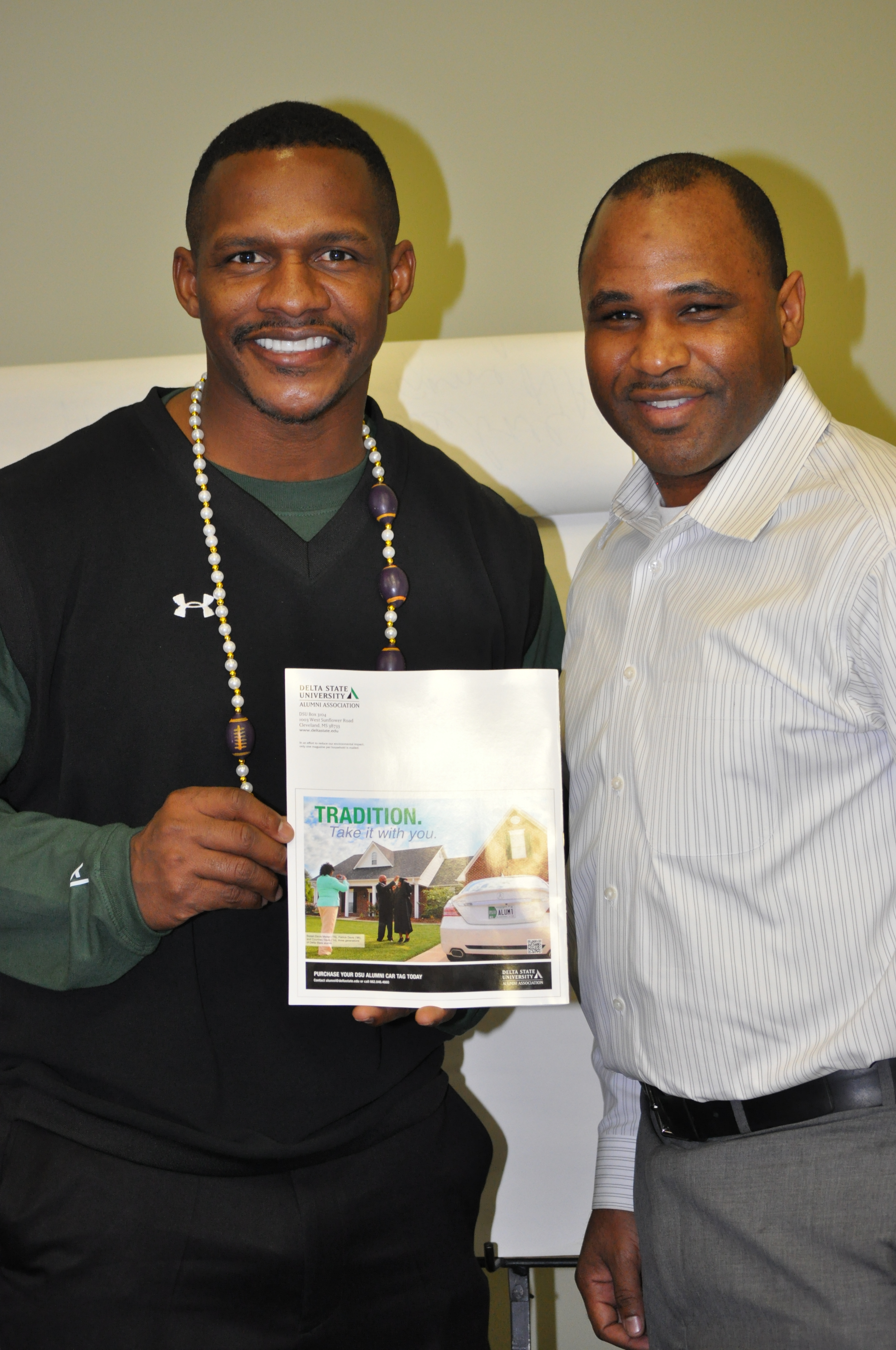PHOTO:  Former New Orleans Saints wide receiver Joe Horn (friend) and Patrick Davis (’96) show off the latest Delta State University license plate advertisement on the back cover of the Delta State Alumni Magazine, which features Davis and his family, three generations of Delta State alumni with DSU car tags.